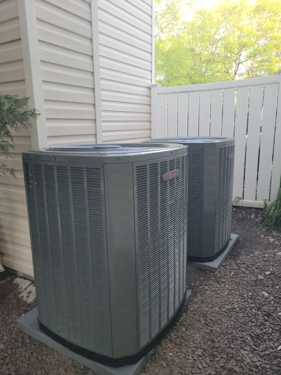 Two Trane central air condensers installed alongside home